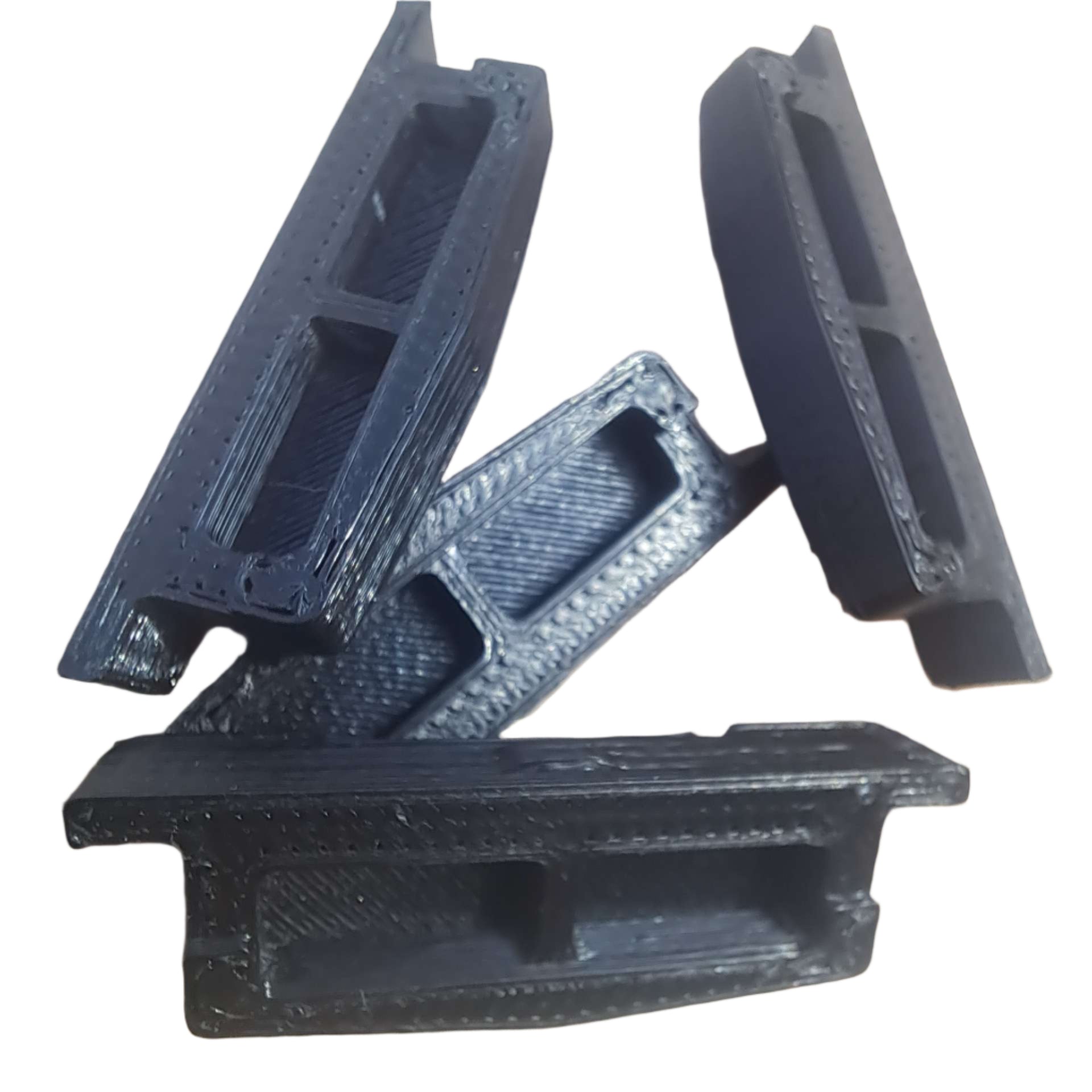 Four black 3D-printed plastic parts on a light-colored surface