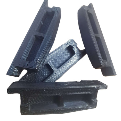 Four black 3D-printed plastic parts on a light-colored surface